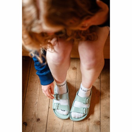 Obenansicht einer Person, die sich zu ihren Schuhen herunterbeugt