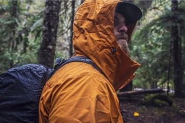 ein Mensch läuft durch den verregneten Wald